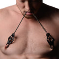 Master Series black Japanese nipple clamps with chains held in a man’s mouth.