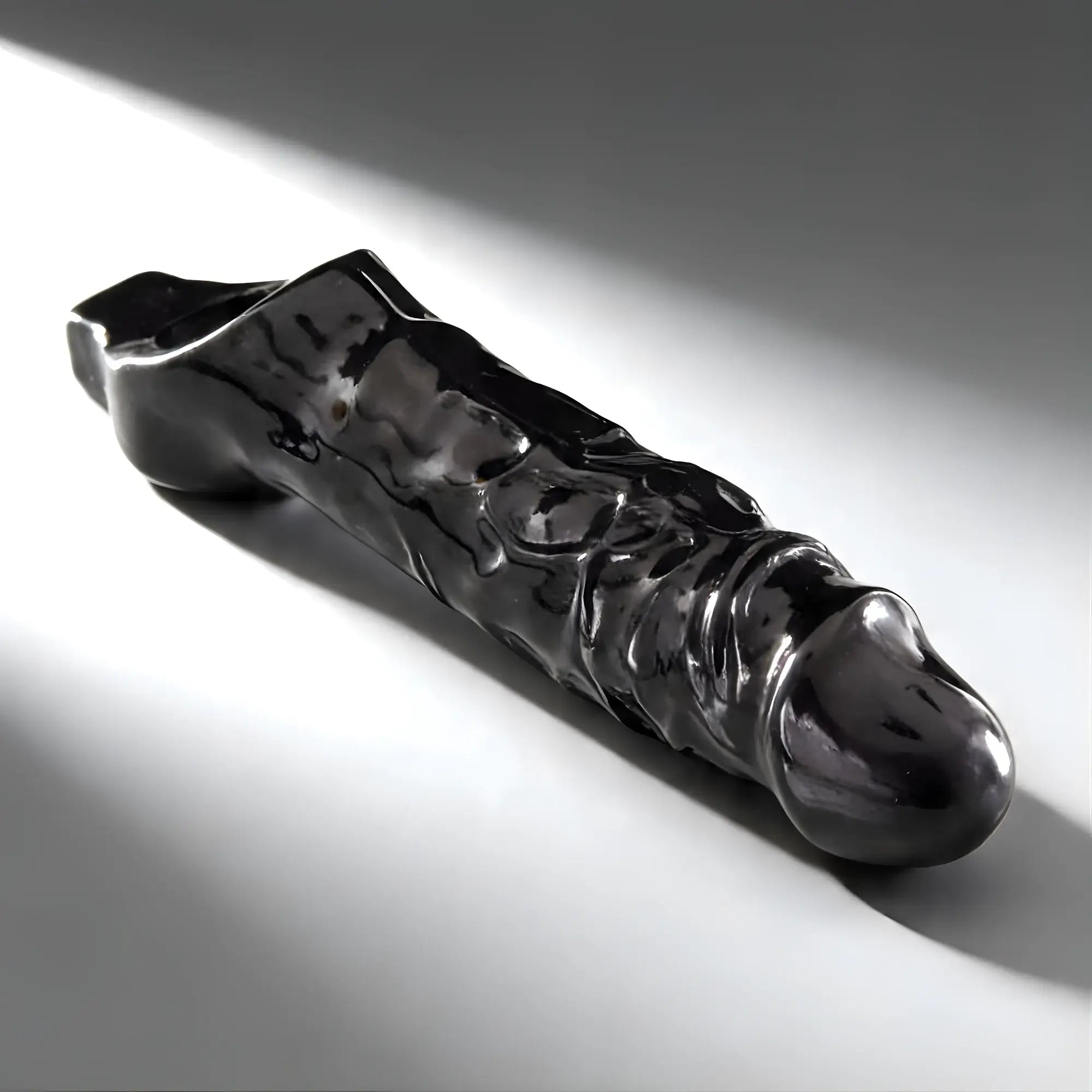 Master Series Black Mamba cock sheath in glossy black with a textured, realistic design on a light background.