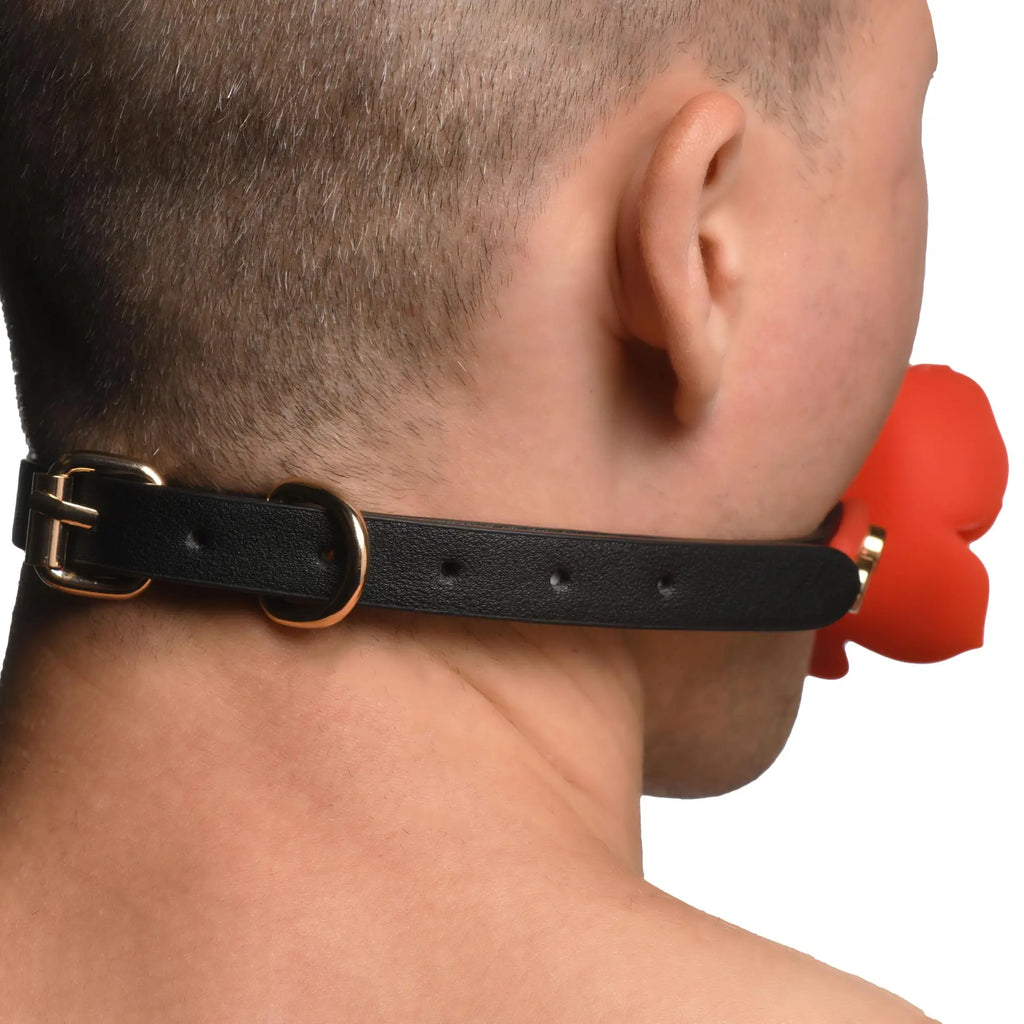 Master Series Blossom Silicone Breathable Rose Gag with a black leather strap and gold hardware worn by a person.