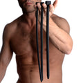 A shirtless man holds three long, black silicone Master Series Bolted Deluxe Urethral Sounds with square bases.