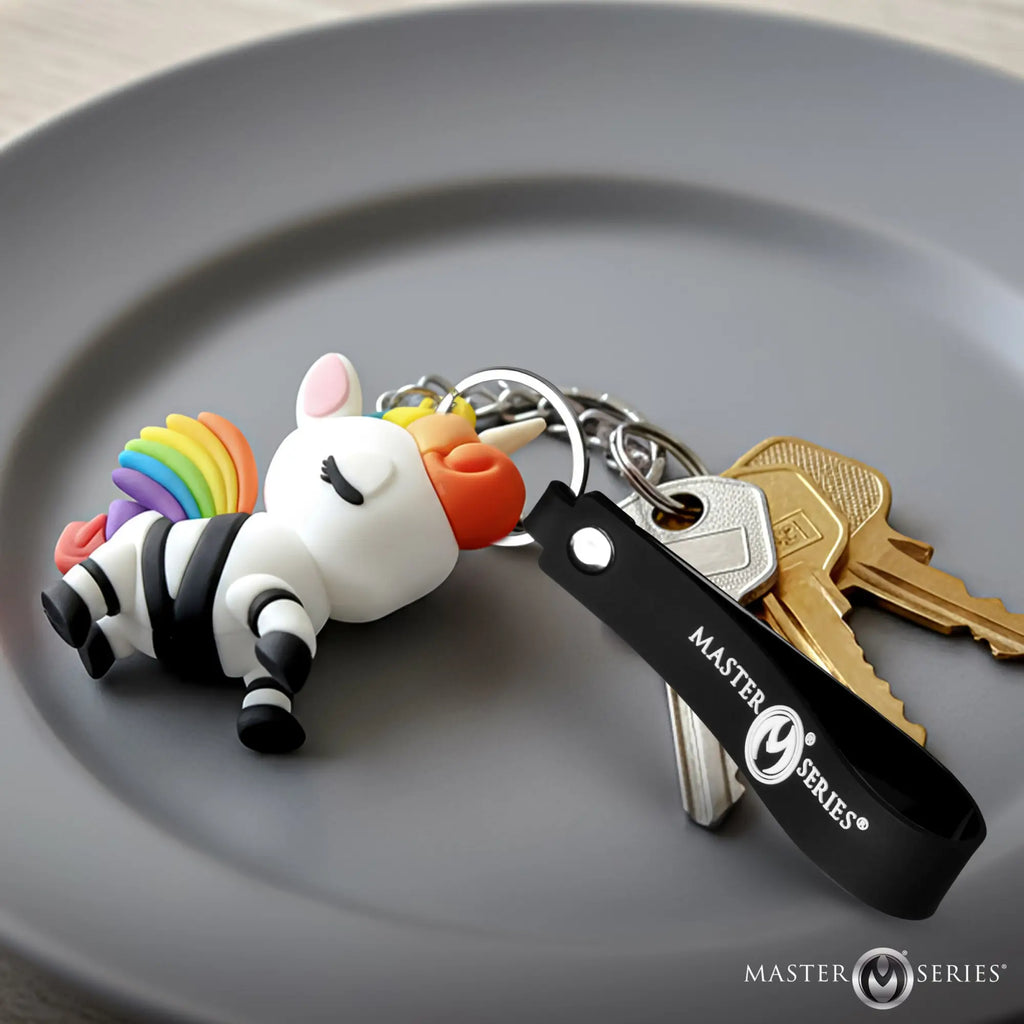 Master Series Bondage Unicorn keychain with rainbow mane, black straps, and silver hardware on a gray plate with keys.