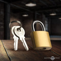 Master Series brass collar padlock with a silver shackle and two matching keys on a keyring, set on a wooden surface.