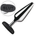 Master Series silver metal butt plug with a black silicone base featuring the debossed text "SLUT" on the end.