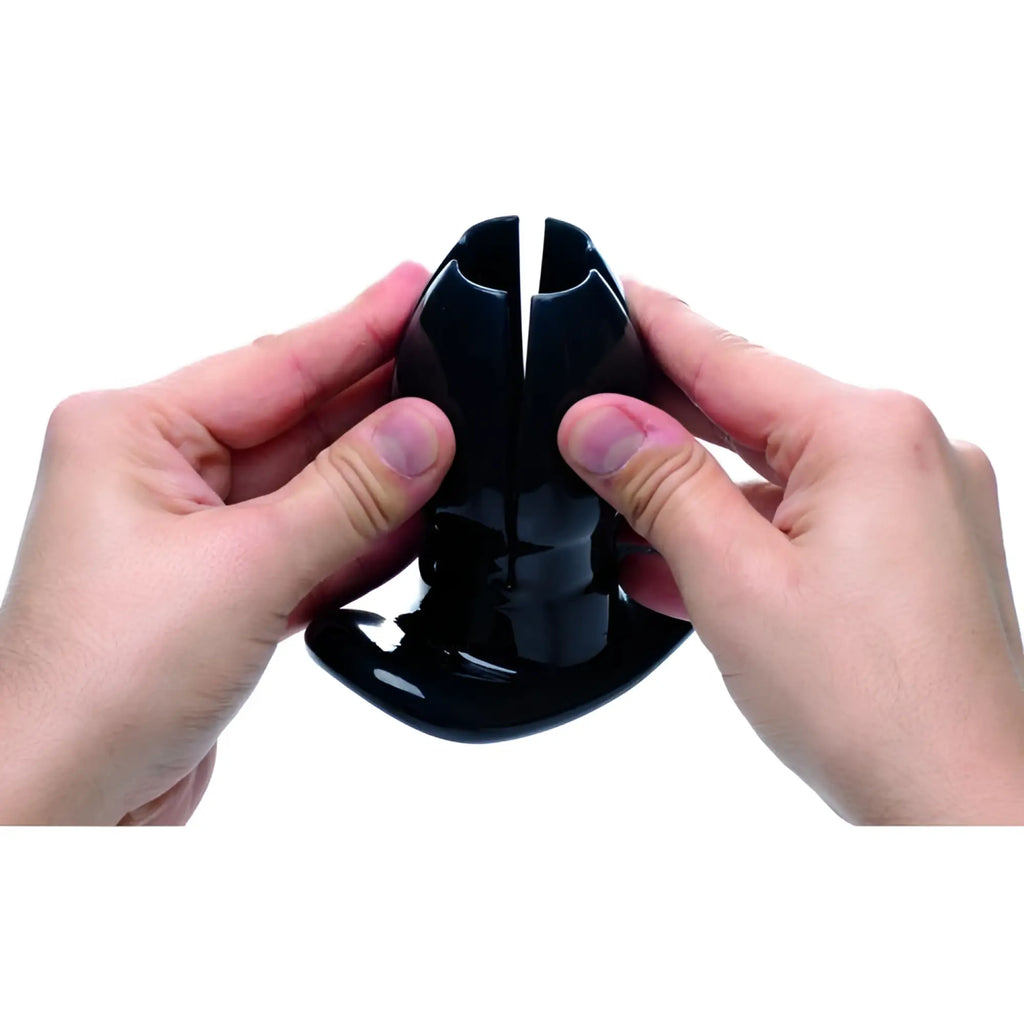 Hands holding a black, shiny Master Series Claw expanding anal dilator against a white background.