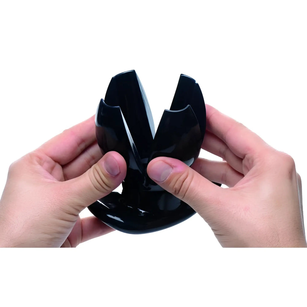 Hands holding a black, claw-style Master Series expanding anal dilator against a white background.