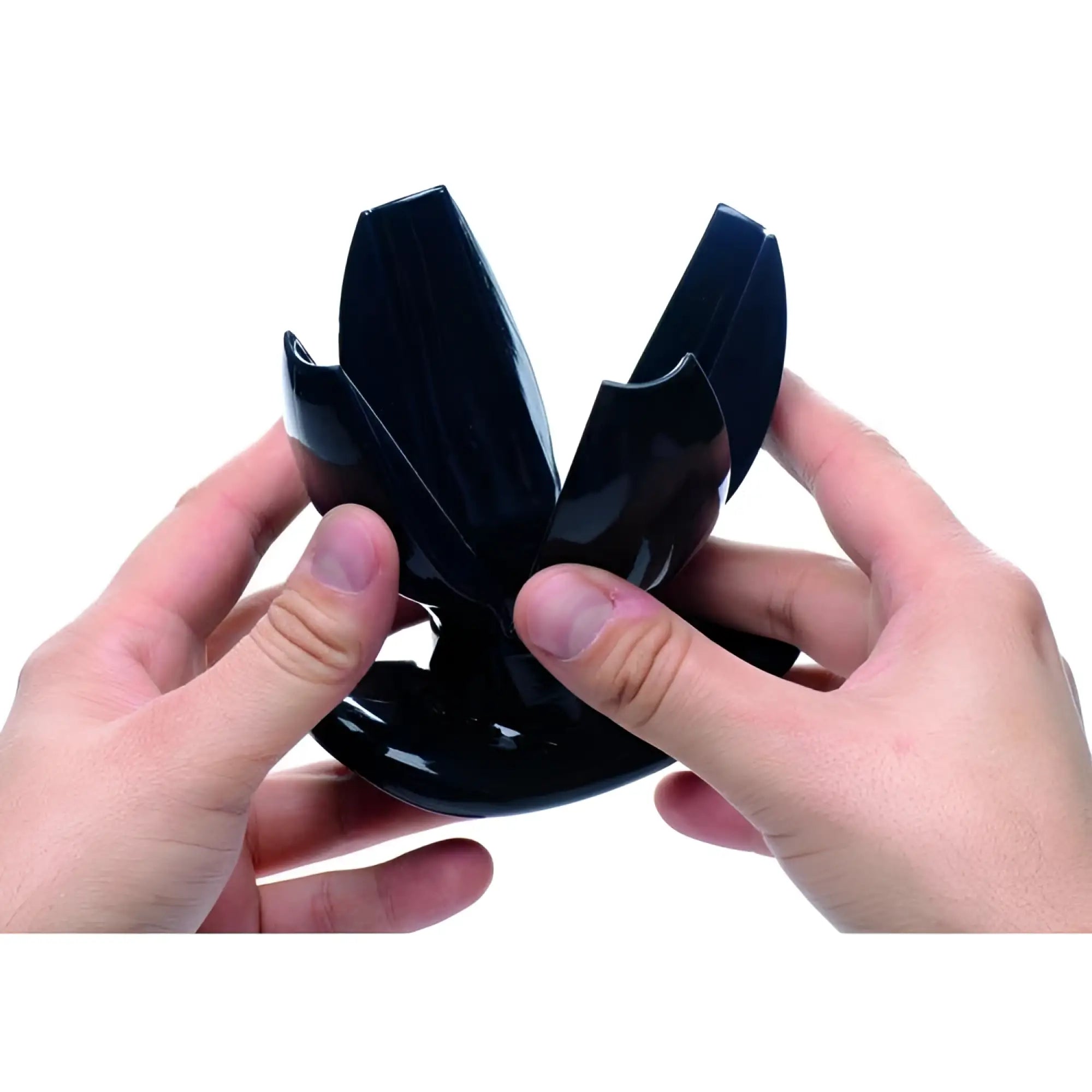 Hands holding a black Master Series Claw Expanding Anal Dilator in its open, petal-like position against a white background.