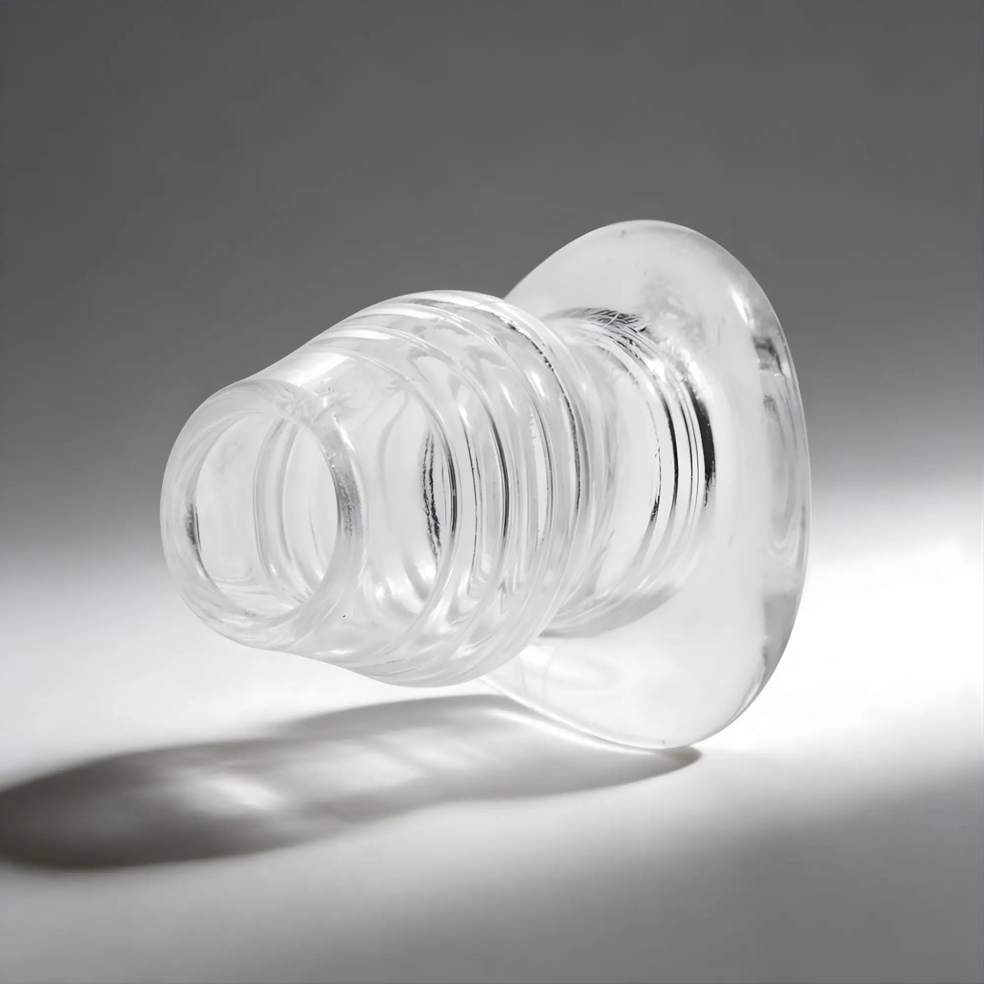 Master Series The Cock Dock: a hollow, clear glass butt plug featuring a ribbed design and a flared circular base.
