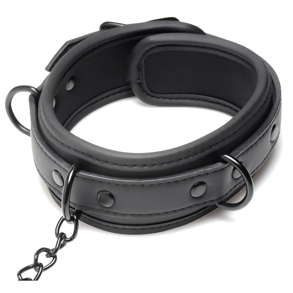Master Series black faux leather collared Temptress collar with connected chains and rings, isolated on a white background.