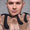 A man holding three black, curved silicone Master Series Dark Delights anal trainers of different sizes.