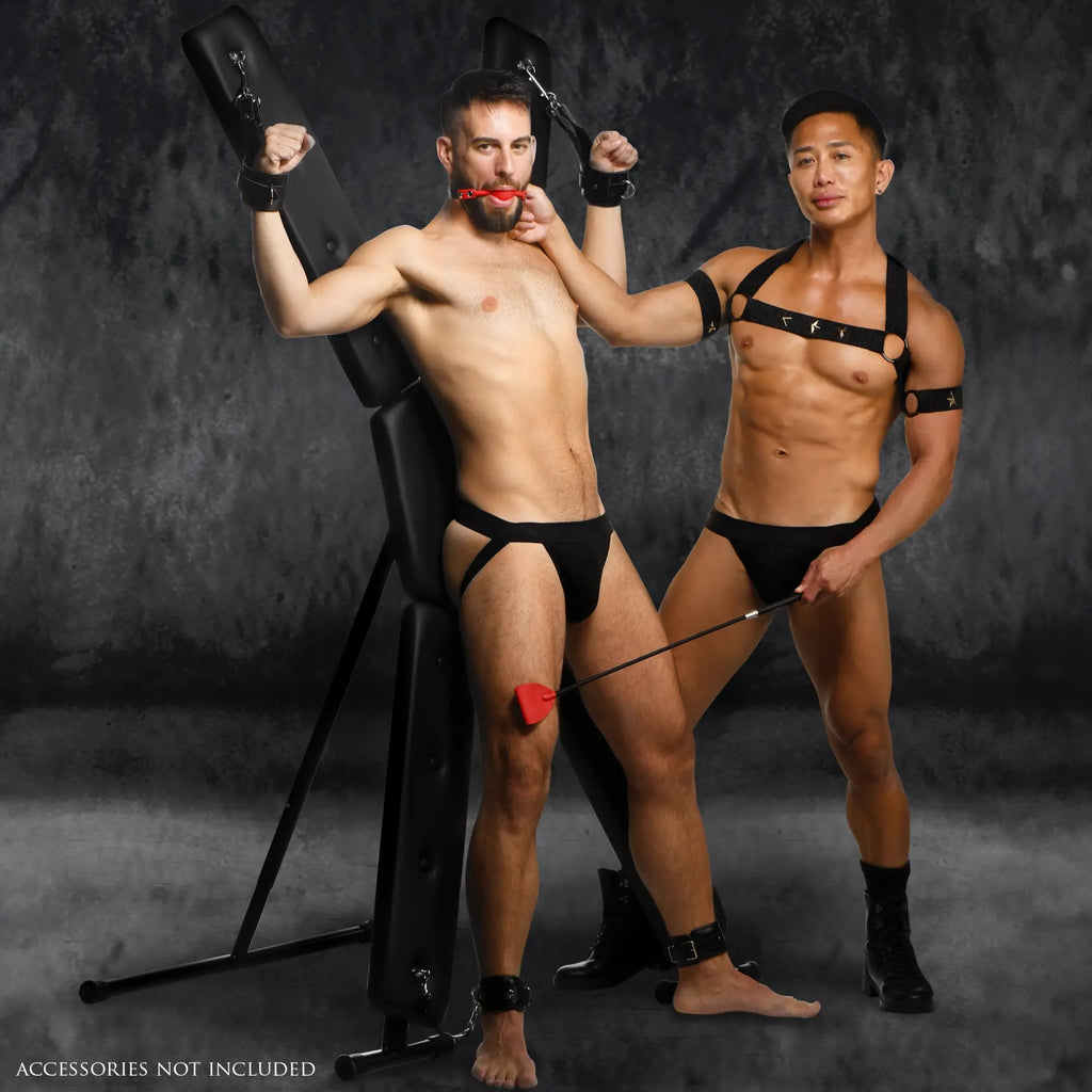 Master Series Deluxe St. Andrew's Cross: A padded black X-frame for bondage with metal hardware on a grey background.