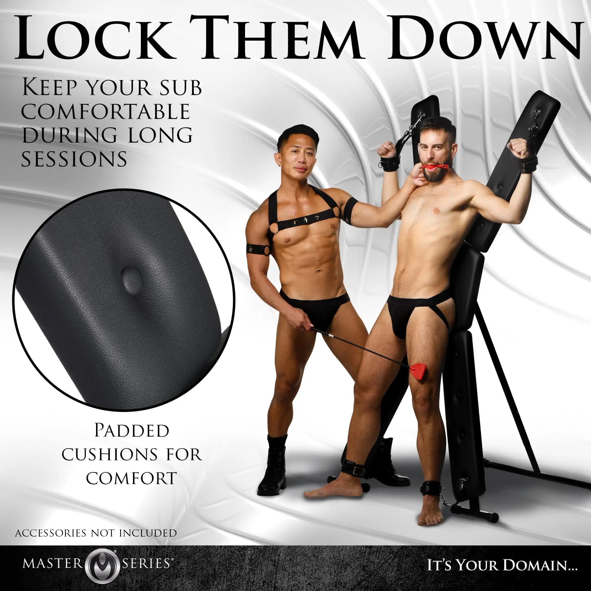 Master Series Deluxe St. Andrew's Cross: A black, padded X-frame restraint stand used by two men in a studio setting.
