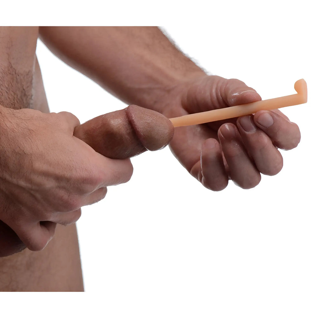 A hand holding a beige silicone urethral sound from the Master Series Dockers set against a white background.