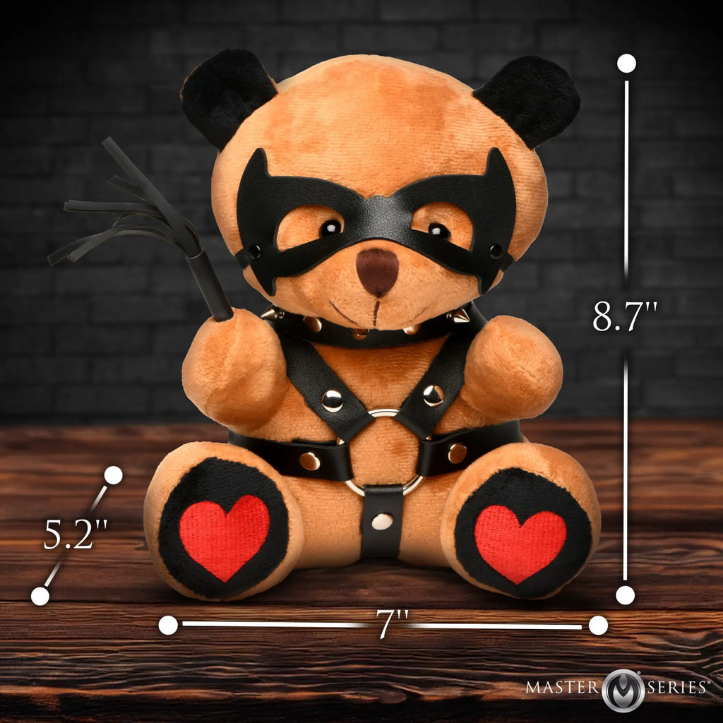 Master Series Dom Teddy Bear: A tan plush bear wearing a black eye mask, spiked collar, harness, and holding a whip.
