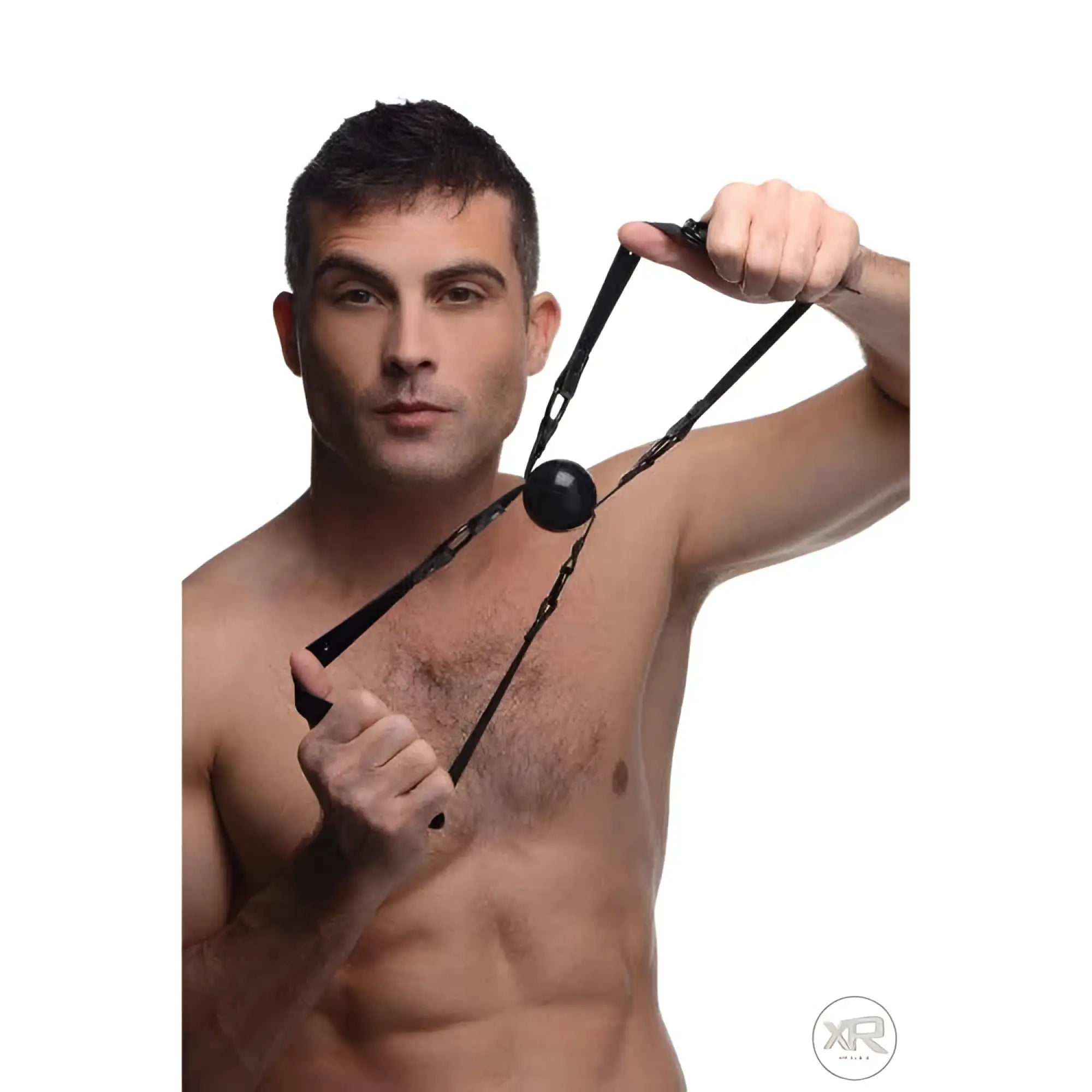 A shirtless man holds a black Master Series Doppleganger silicone ball gag with adjustable straps against his chest.