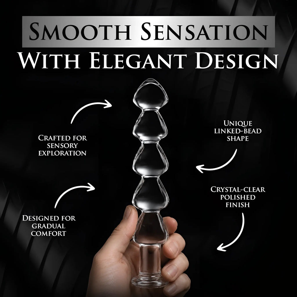 Master Series Drops Anal Link glass dildo: a crystal-clear, beaded-style toy held in hand against a black background.