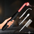 Hand holding a black Master Series Elektrawand with a glowing red glass electrode and three clear glass attachments.