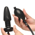 Master Series Expand Inflatable Anal Plug: black silicone plug with a matching hand pump, held against a white background.