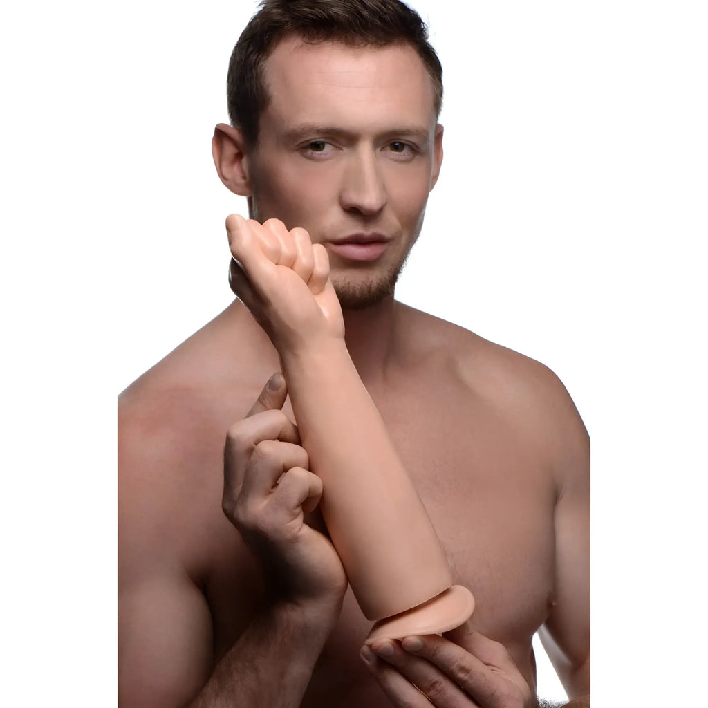 Man holding a beige, realistic Master Series Fisto clenched fist dildo against a white background.