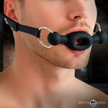 Master Series black silicone feeding gag with adjustable leather straps worn on a man’s face.