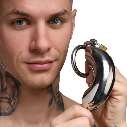Man holding a polished, silver-tone stainless steel Master Series Forged Captor locking chastity cage with a small lock.