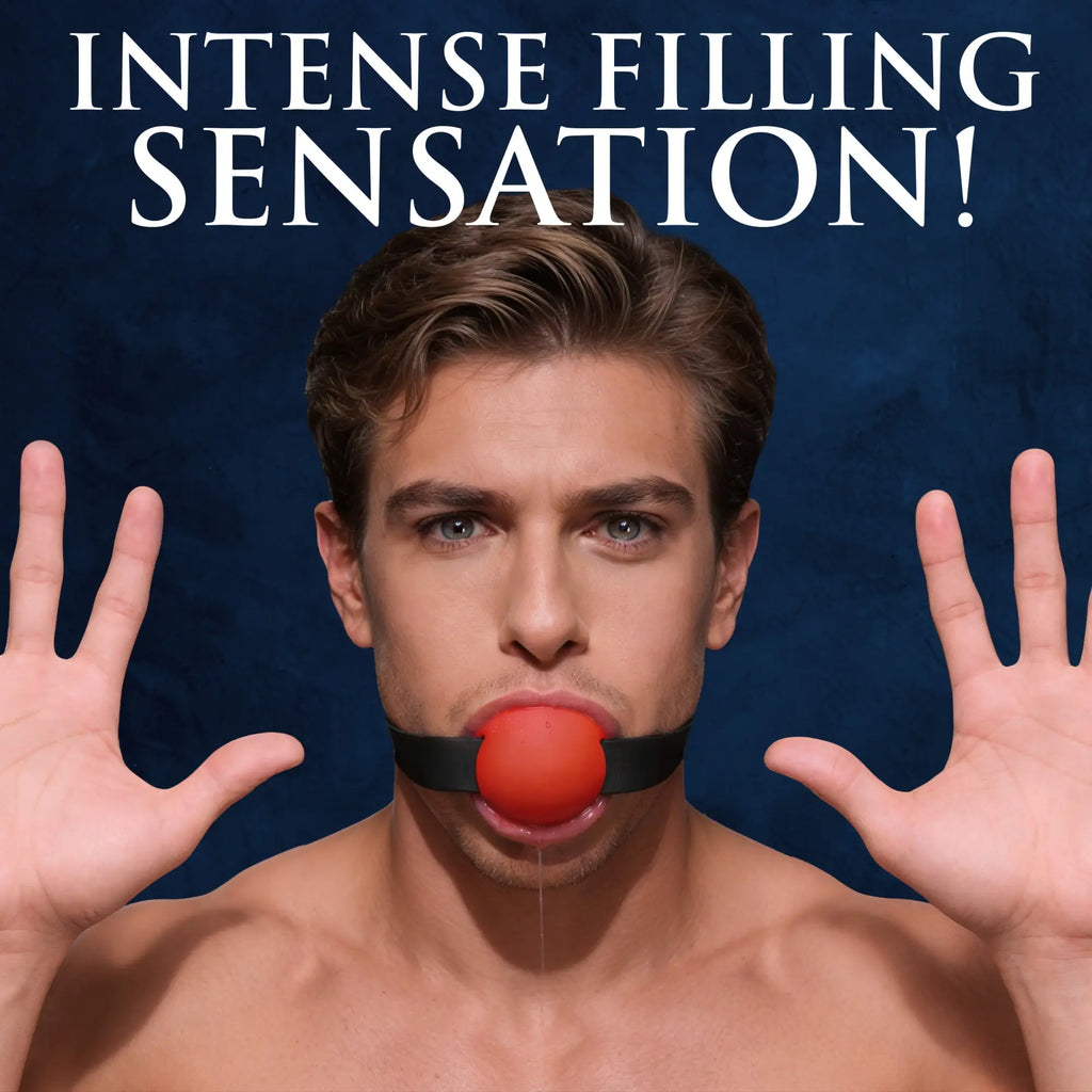 Master Series Gag Order silicone ball gag: a man wearing a red ball gag with a black strap, hands raised, blue backdrop.