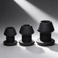 Master Series Gape-Grommets: A set of three graduated, matte black hollow silicone anal dilators on a grey background.
