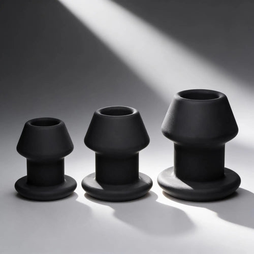 Master Series Gape-Grommets: A set of three graduated, matte black hollow silicone anal dilators on a grey background.