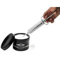 Master Series The Grease Gun: a metal syringe tool scooping white Invade Deep Fisting Cream from a black jar.