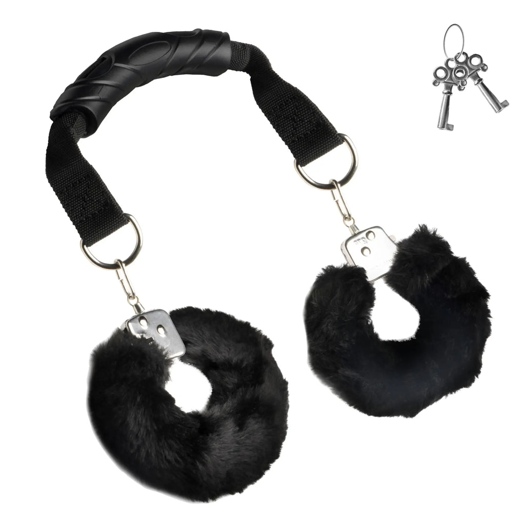 Master Series The Handler: black furry handcuffs attached by straps to a central black handle, with two keys.
