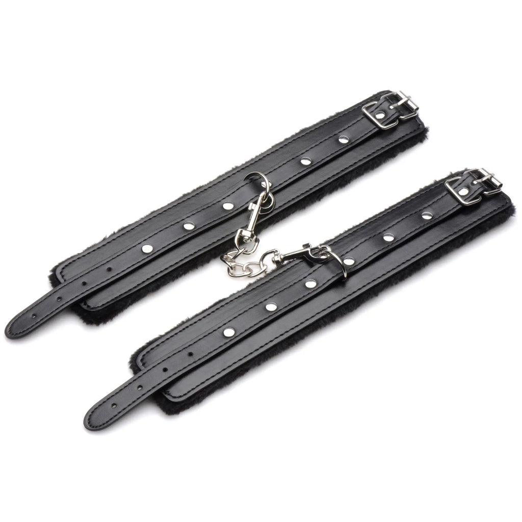 Master Series Hook Up plush bondage cuffs in black, featuring soft lining, silver-toned buckles, and a connecting chain.