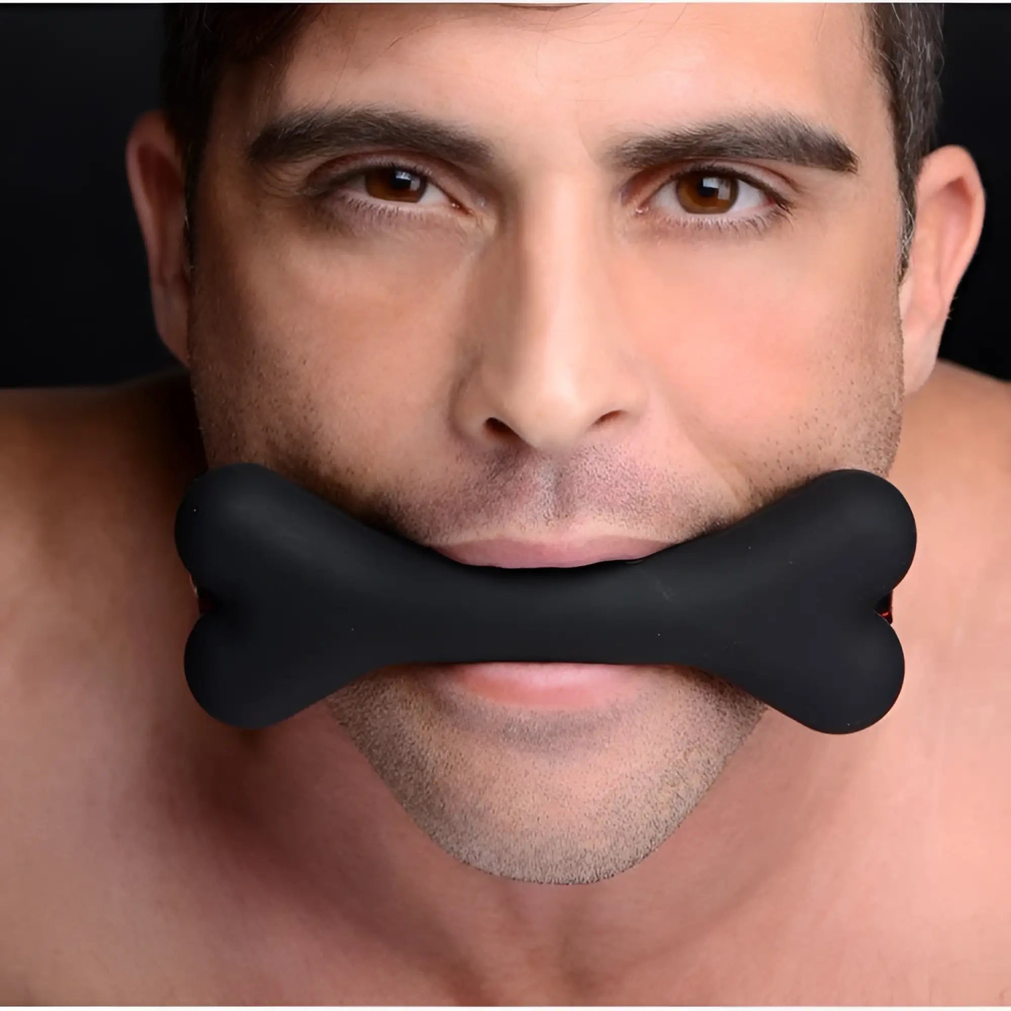 Close-up of a man wearing a black Master Series Hound adjustable bone-shaped silicone gag.