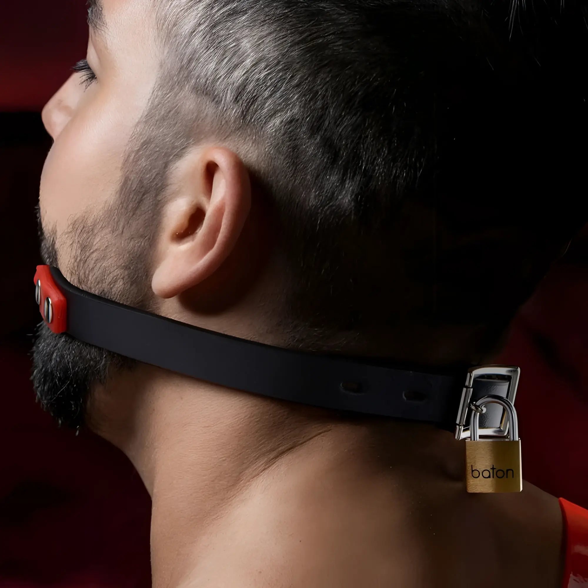 Master Series Hush Comfort silicone ball gag in black with red accents, secured with a gold baton padlock.