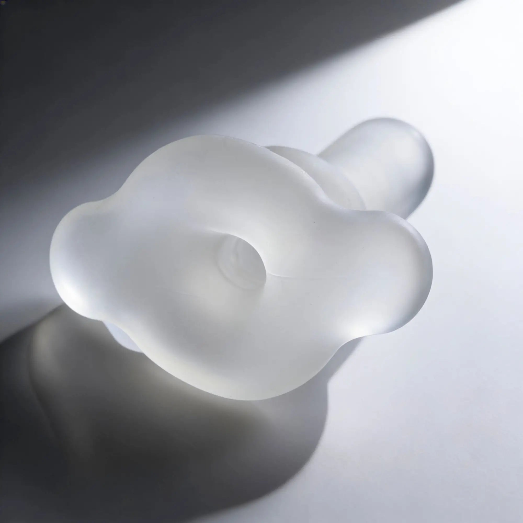 Master Series Inception Sheath: A clear, cloud-shaped silicone intimate toy with a centered opening on a white surface.