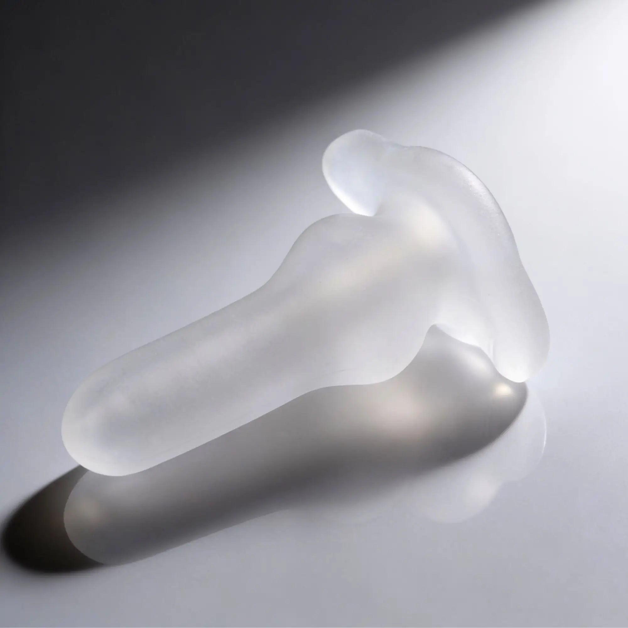 Master Series Inception Fuckhole Sheath: A clear, frosted, contoured silicone pleasure toy on a reflective surface.