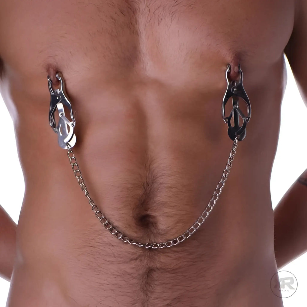 Master Series Japanese Clover Clamps: silver metal nipple clamps connected by a decorative chain on a male torso.