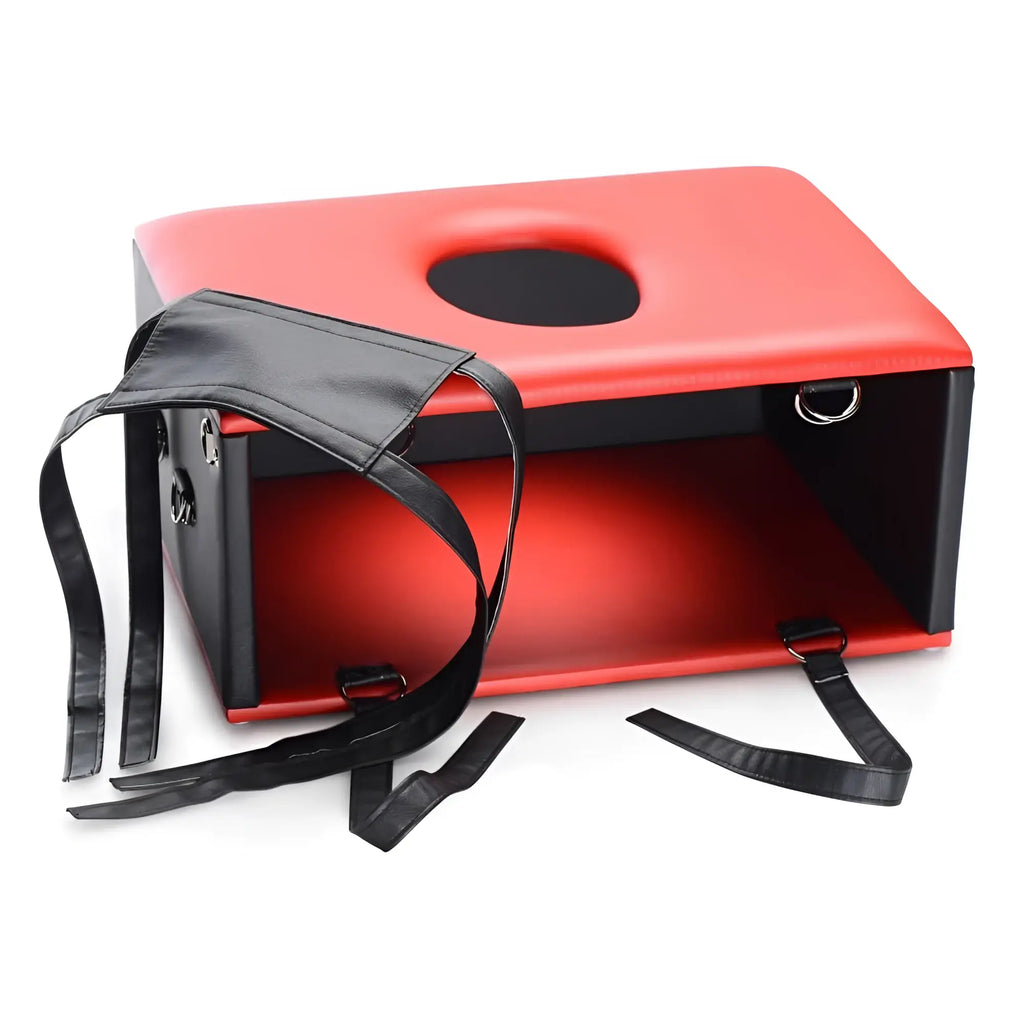 Master Series The Kinging Chair: A red and black padded stool with a central cutout and attached black restraint straps.