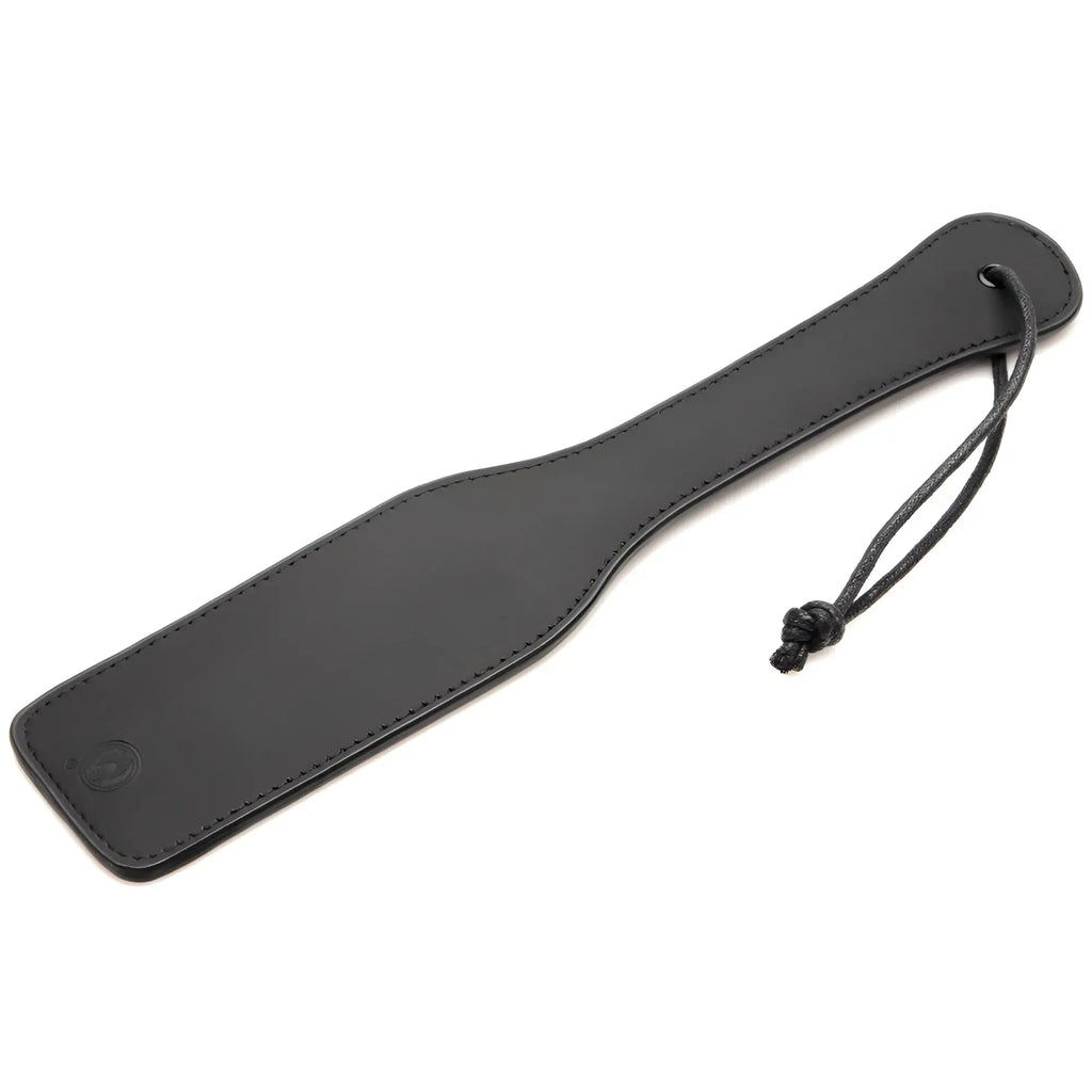 Master Series paddle from the Master of Kink set, a black faux leather sensory paddle with a matching wrist strap.