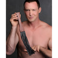 Shirtless man holding a Master Series Master Lasher wooden flogger with a brown handle and black leather tails.