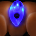 Master Series Light-Tunnel anal dilator, a glowing blue, semi-translucent teardrop toy against a skin-tone surface.