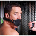 A man wearing a black leather, inflatable Master Series Locking Pump Gag with a hand-held inflation bulb.