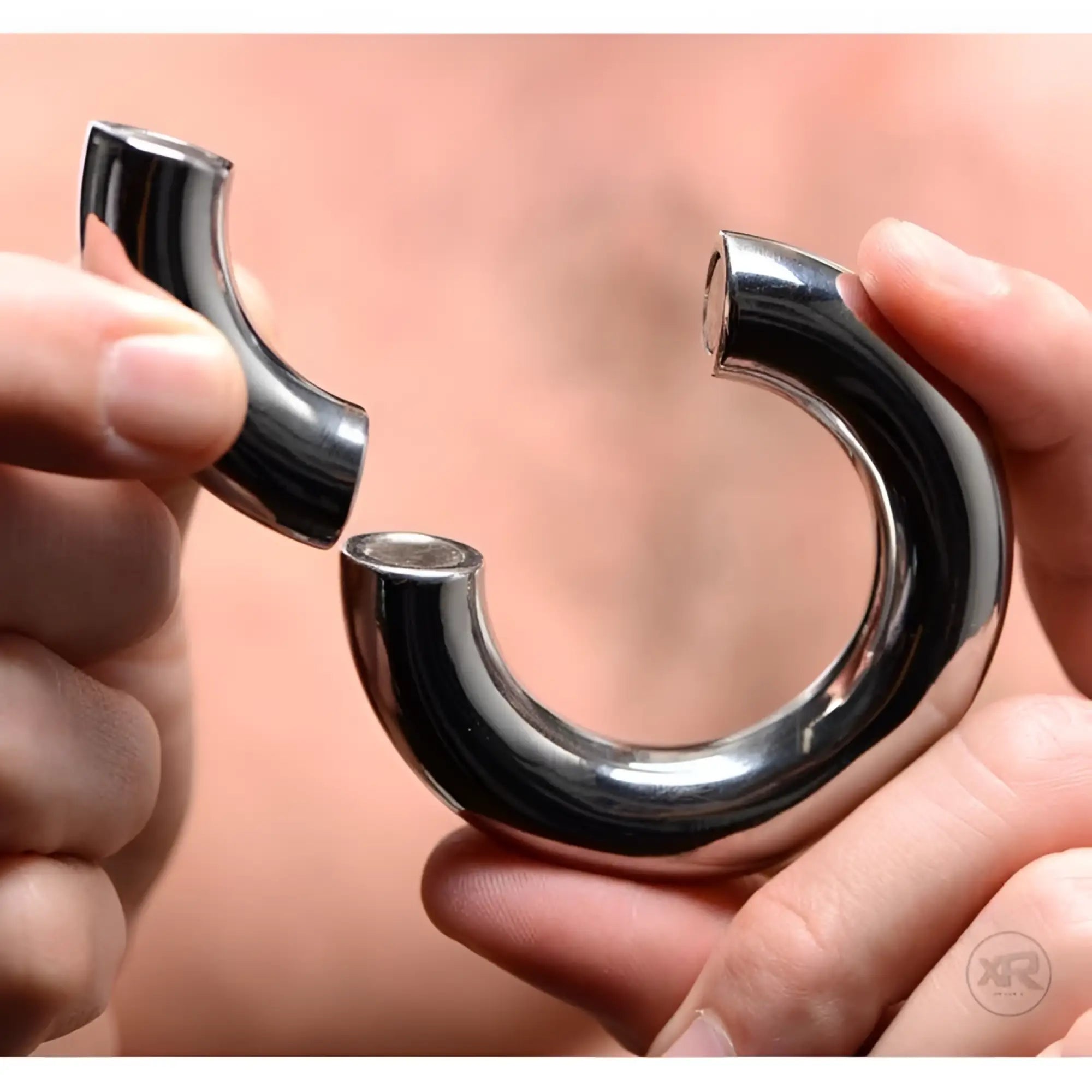 Master Series Magnetize: Hands hold a polished, silver stainless steel magnetic ball stretcher in two pieces.