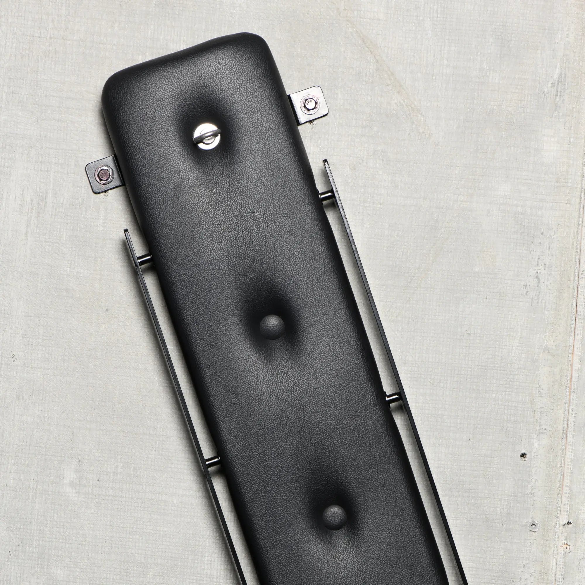 Master Series St. Andrew's Cross: A padded, black leather-textured arm with metal hardware on a grey background.