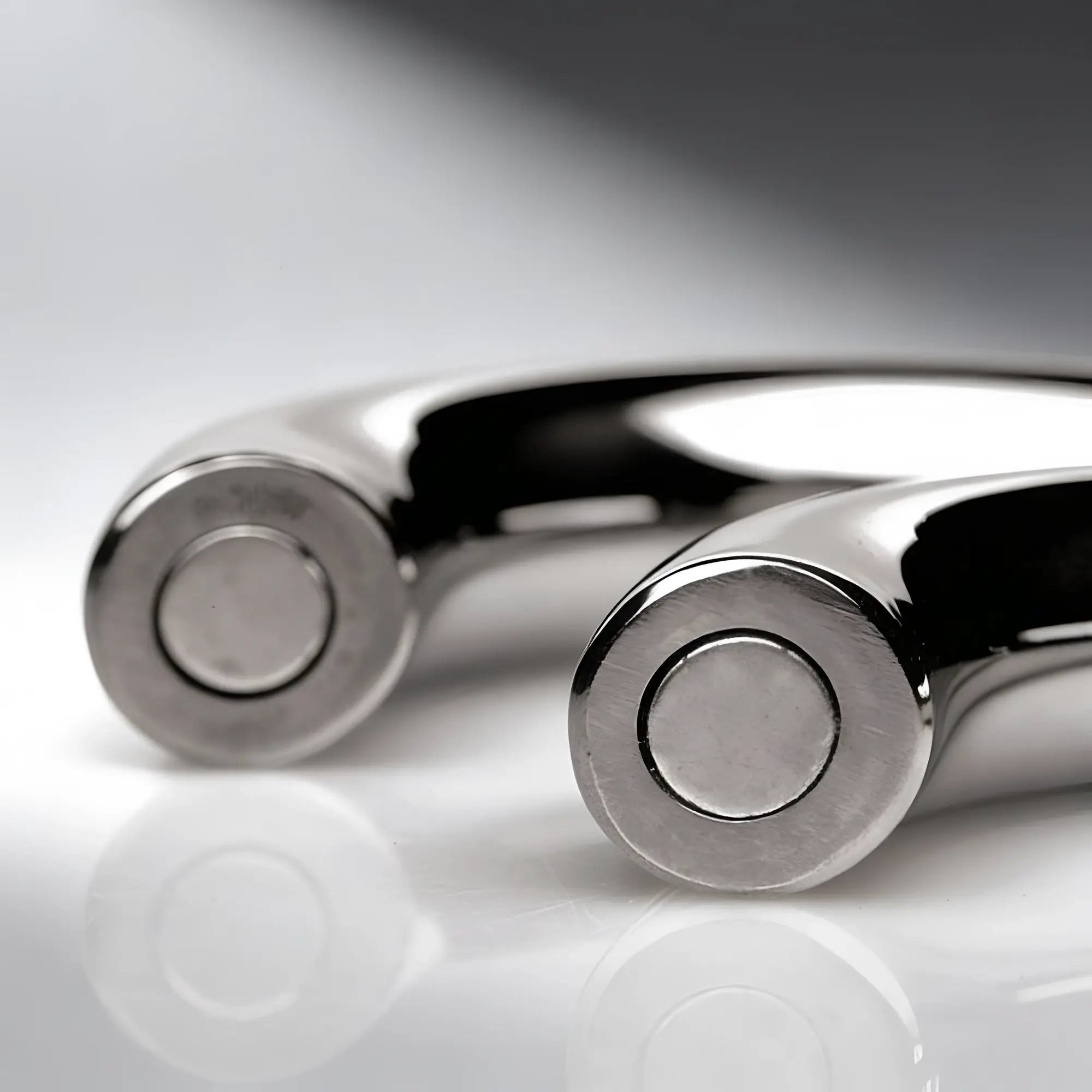 Master Series Mega Magnetize silver stainless steel cock ring with circular magnetic clasps on a reflective surface.