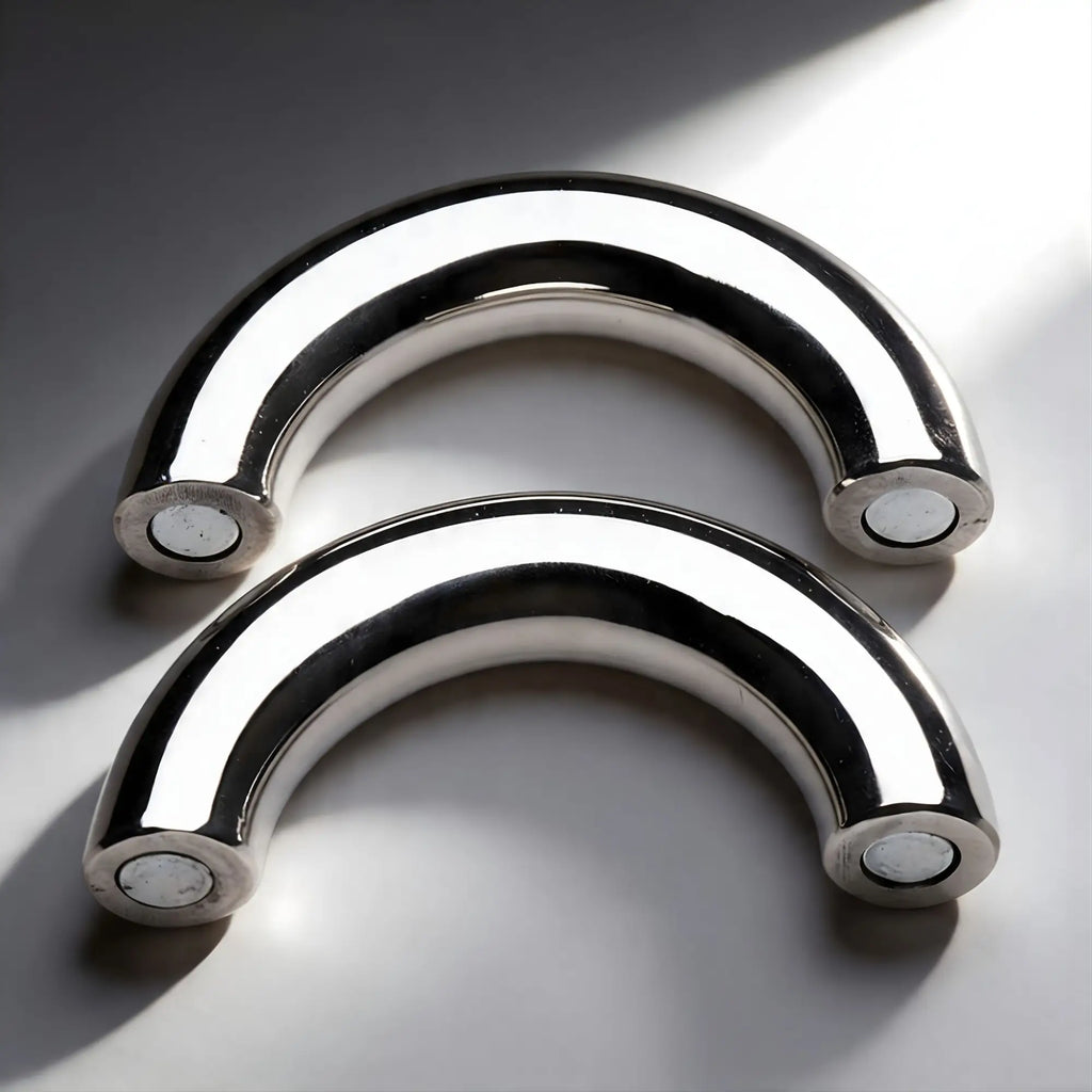 Two polished stainless steel Master Series Mega Magnetize curved magnetic cock rings on a white background.