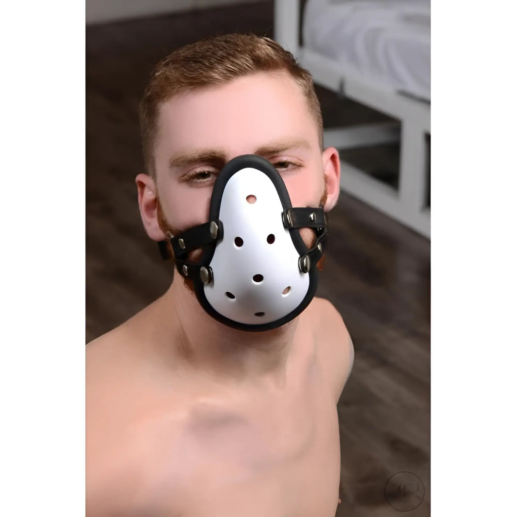 A man wearing a white, vented Master Series Musk Athletic Cup Muzzle with black leather straps and silver hardware.