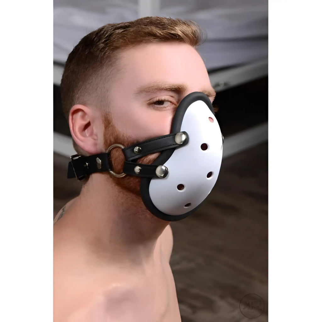 Master Series Musk Athletic Cup Muzzle: A man wearing a white, vented, cup-style mask with black leather straps.