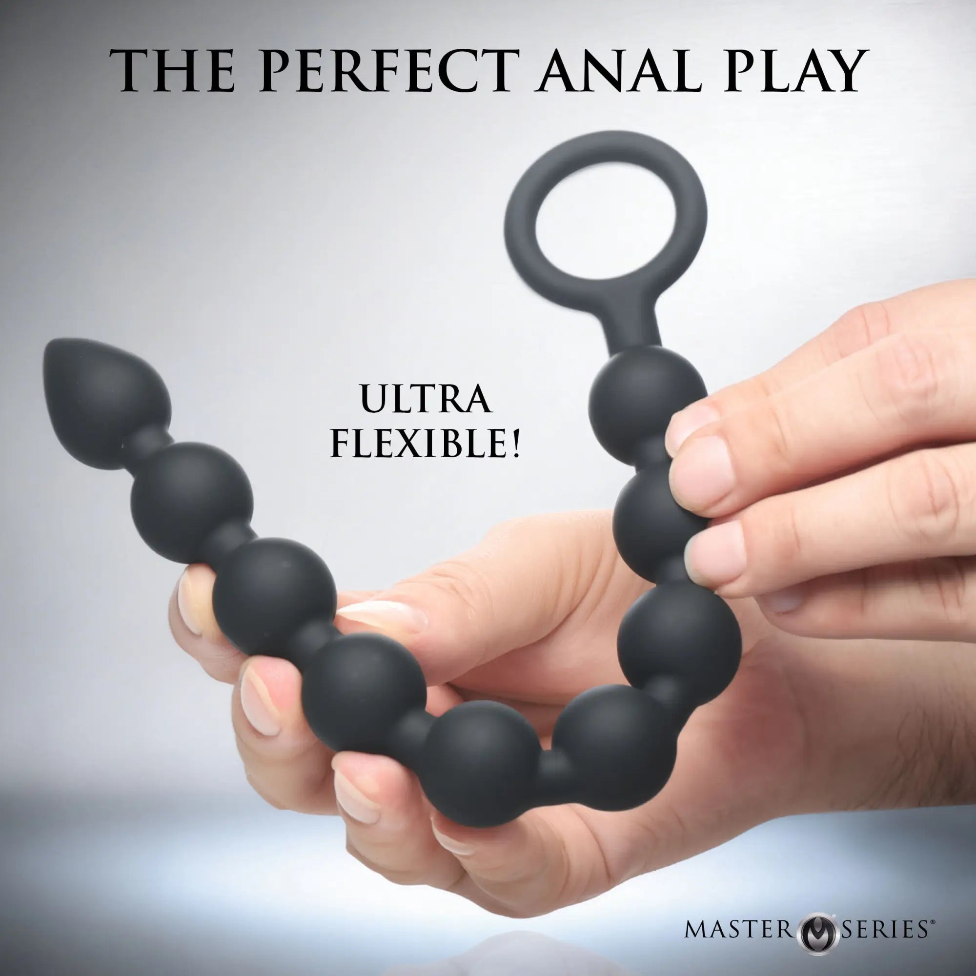 Master Series Pathicus: Flexible black silicone 9-bulb anal beads with a pull ring, held by a hand.