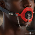 Master Series Plugged Silicone Feeding Gag: red silicone lip gag with black plug, chain, and black leather strap.