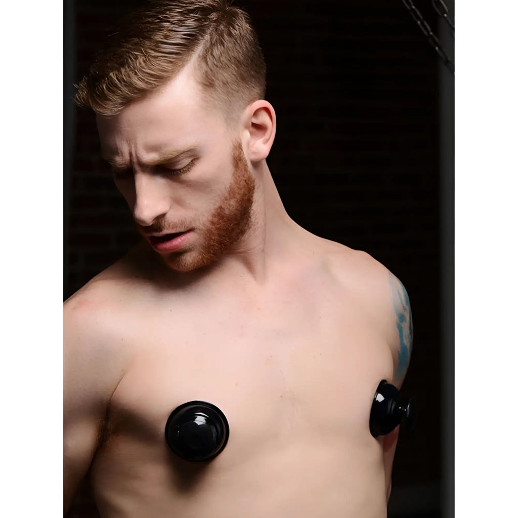 Man wearing black Master Series Plungers silicone nipple suckers on his bare chest.
