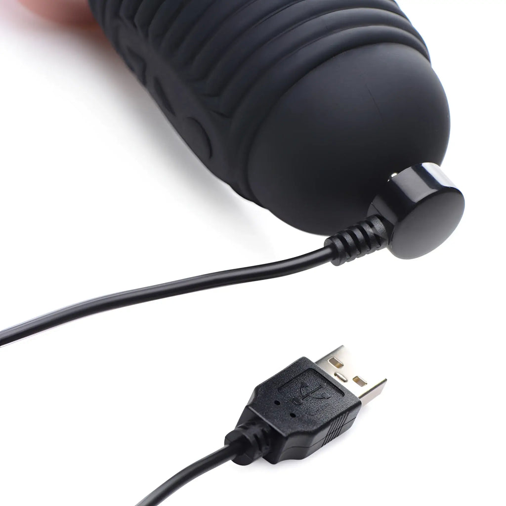 Master Series Power Pounder silicone dildo in black with a ribbed texture, shown attached to its magnetic USB charger.